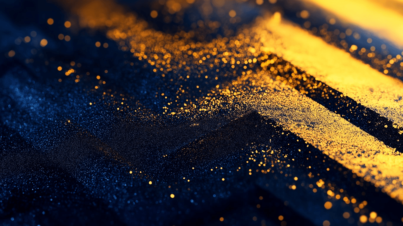 Close-up of dark, textured surface with scattered golden particles illuminated by light.